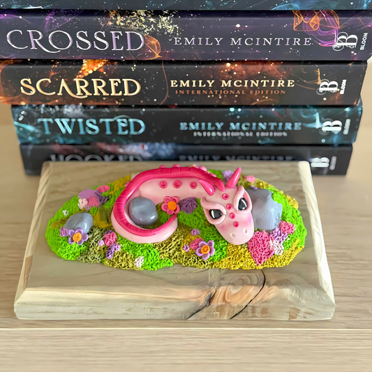 Whimsical Pink Dragon Figure Laying Amongst The Rocks.